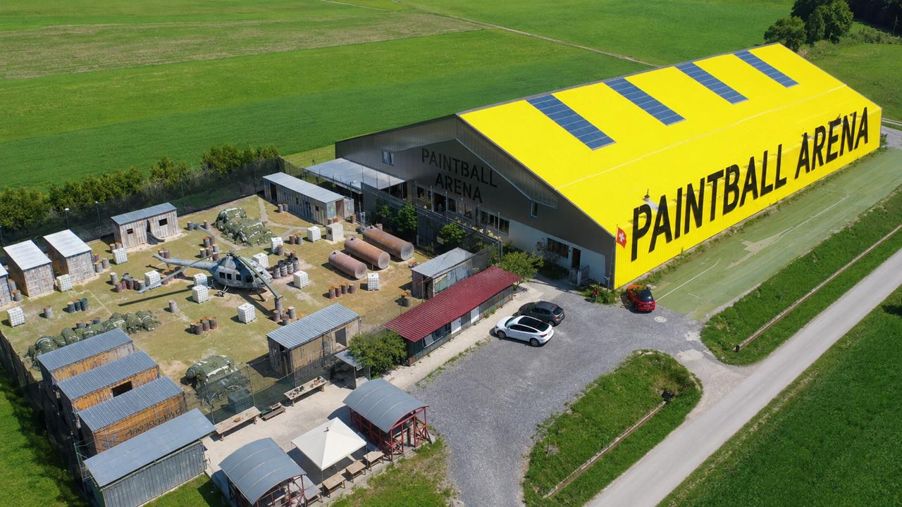 Luftaufnahme der Paintball Arena: Outdoor-Spielfeld mit Bunkern und die gelbe Halle